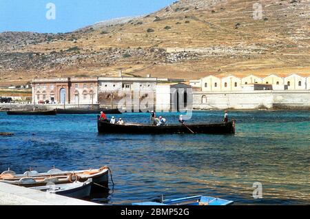 Îles Aegadiennes, Sicile, Italie. Mai 1983. Tonnara et mattanza. Bateau de pêche au thon sur l'île de Favignana. En arrière-plan l'usine de Tonnara. Banque D'Images