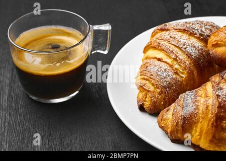 Tasse de café et croissants fraîchement cuits sur une table sombre. Concept petit déjeuner servi. Pâte française à base de pâte feuilletée Banque D'Images