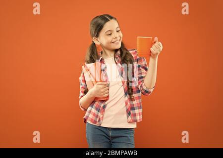 Dépenser temps agréable avec livre préféré. Fille tenir une tasse de thé et d'adresses. La littérature pour enfants. Aime passer du temps à la maison. Cacao chaud et bon livre idéal pour soirée agréable. Lecture bucket list. Banque D'Images