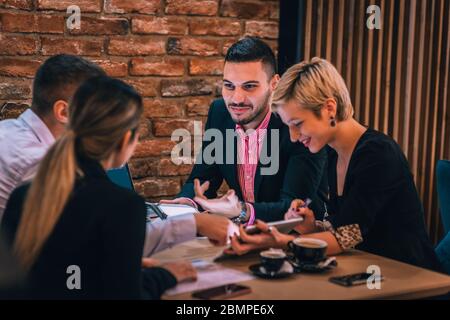 Divers collègues, partager leurs idées sur le projet et analyser les statistiques et la stratégie tout en appréciant leur café dans un café. Banque D'Images