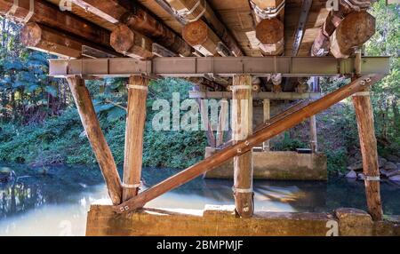 Sous un pont en bois et en acier construit avec des ruses, au-dessus d'une crique dans une forêt tropicale Banque D'Images