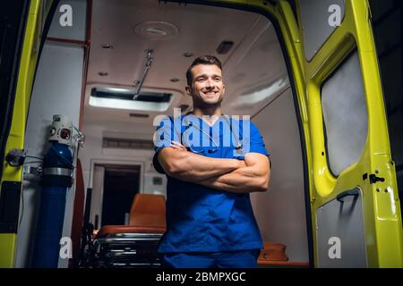 Jeune médecin debout et souriant devant un an voiture d'ambulance Banque D'Images