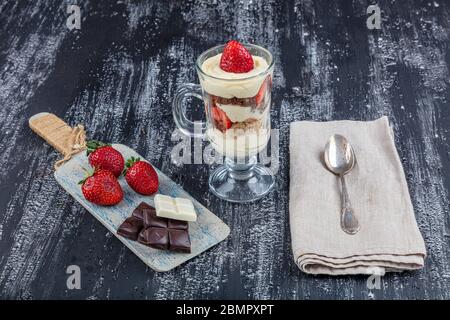 Magnolia dessert. Dessert au magnolia fraise dans une tasse en verre sur fond de bois. Banque D'Images