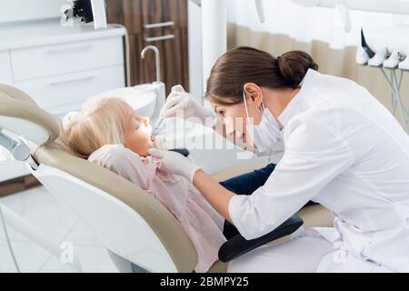 Une belle femme dentiste examinant les dents de la petite fille Banque D'Images