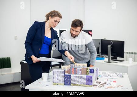 Les jeunes employés du bureau d'architecte discutant du mod de construction Banque D'Images