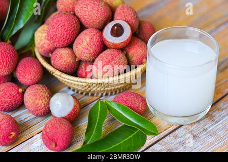 Boisson fraîche au litchi et tranche épluchée avec des feuilles vertes récolte dans le panier de fruits tropicaux arbre été en Thaïlande / jus de Lychee sur table en bois Banque D'Images