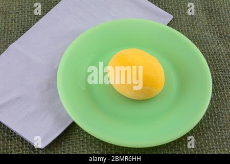 Boule de mochi de glace Mango sur une assiette de dessert verte avec serviette lavande Banque D'Images