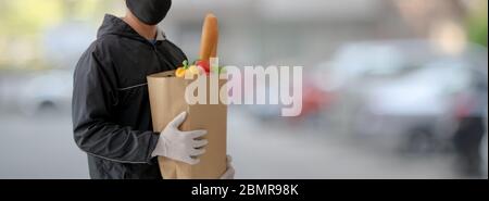 Photo de l'homme du service de livraison de nourriture tenant un sac de nourriture fraîche en attendant son client Banque D'Images