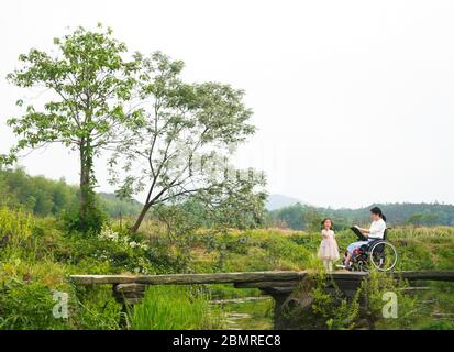 (200511) -- BEIJING, 11 mai 2020 (Xinhua) -- Zhang Haijing peint avec sa fille près de leur maison dans la ville de Dagang, comté de Duchang, province de Jiangxi, en Chine orientale, le 7 mai 2020. Zhang Haijing, 30 ans, né à Lishui, dans la province de Zhejiang, dans la ville de Lishui, dans l'est de la Chine, a été laissé en fauteuil roulant après un accident en 2008. Un an plus tard, Zhang a trouvé son intérêt pour la peinture et a commencé à apprendre l'artisanat. Le nouveau passe-temps l'a aidé à se remettre progressivement des séquelles douloureuses de l'accident. Zhang a rencontré Dan Yuchao, un homme qui a perdu sa main droite, en 2014 et ils sont rapidement tombés amoureux l'un de l'autre comme l' Banque D'Images