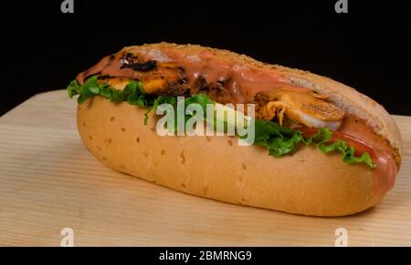 Dinde de de poulet croustillante au poulet avec laitue et tomates servies sur fond sombre de table en bois. Banque D'Images