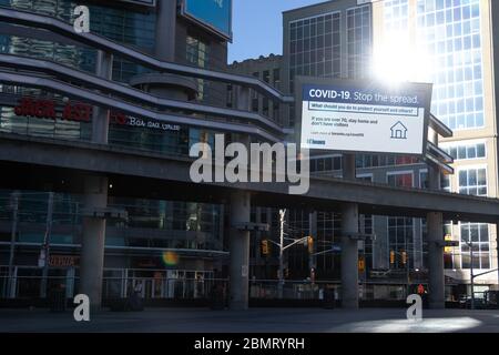 Panneau d'information public “COVID-19 Stop the spread” dans le Square Young-Dundas à Toronto. Soleil brillant d'un bâtiment en arrière-plan. Banque D'Images