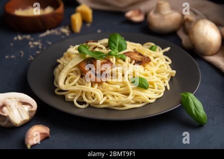 Pâtes italiennes aux champignons et au fromage sur fond sombre. Gros plan Banque D'Images