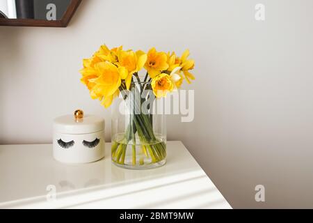 Intérieur moderne et minimaliste, avec fleurs jaunes sur la table, baignée de lumière naturelle depuis la fenêtre Banque D'Images