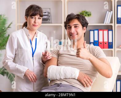 Jeune homme au bras bandé visiter médecin femme traumatologist Banque D'Images