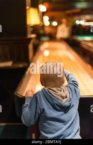 Jeune enfant à capuchon bleu jouant au palets. Banque D'Images