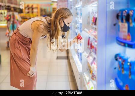 Une femme alarmée porte un masque médical contre le coronavirus lors de l'achat de produits chimiques domestiques dans les supermarchés ou les magasins, en santé, sécurité et pandémie Banque D'Images