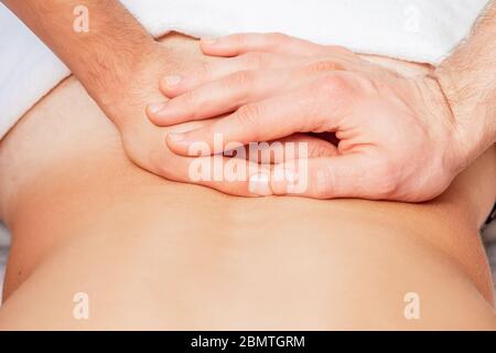 Gros plan des mains du massothérapeute effectuant un massage du dos sur le dos du jeune homme. Banque D'Images