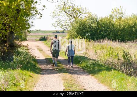 Couple suivant la promenade circulaire de Snettisham à Norfolk vers la côte de la Washington. Banque D'Images