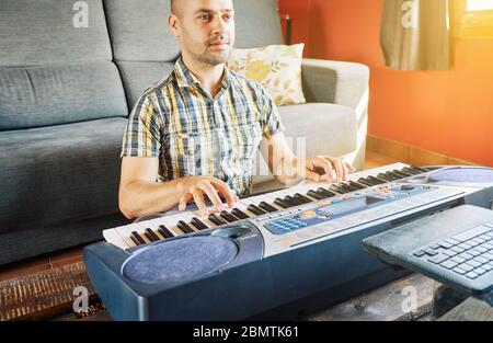 Un homme apprenant à jouer du piano tout en regardant un cours en ligne à la maison Banque D'Images