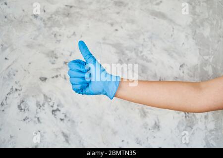 une fille dans un gant bleu montre un signe comme Banque D'Images