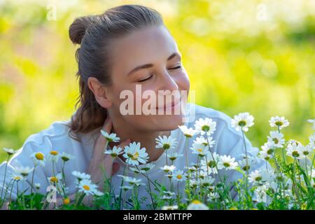 Portrait d'une femme heureuse s'amusant sur le champ de fleurs de Marguerite fraîches, appréciant la chaude journée de printemps ensoleillé et l'arôme des fleurs Banque D'Images