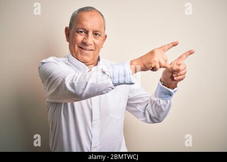 Homme d'affaires senior beau portant une chemise élégante debout sur un arrière-plan rose isolé souriant et regardant la caméra pointant avec deux mains et Banque D'Images