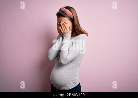 Jeune fille adolescente enceinte s'attendant à bébé sur fond rose isolé frottant les yeux pour la fatigue et les maux de tête, l'expression endormie et fatiguée Banque D'Images