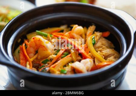 Cuisine asiatique de mer au restaurant. Crevettes cuites en pot avec viande de poulet et légumes frais. Délicieux fruits de mer vietnamiens avec épices en gros plan Banque D'Images