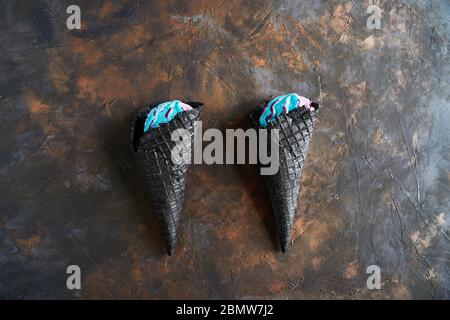 Deux cornets de gaufres noires de crème glacée sur fond sombre, vue du dessus. Banque D'Images