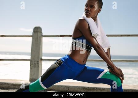 Femme coureur s'exerçant à l'extérieur. Une femme qui fait de l'exercice d'étirement et regarde loin. Banque D'Images