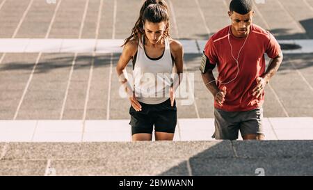 Couple dans l'entraînement de sport ensemble dans la ville. Homme et femme sportifs s'exerçant sur des marches ensemble dans la ville. Banque D'Images