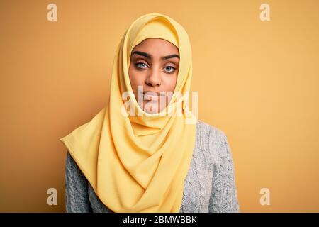 Jeune fille afro-américaine portant le hijab musulman sur fond jaune isolé, qui a l'air endormi et fatigué, épuisé pour la fatigue et la hangove Banque D'Images