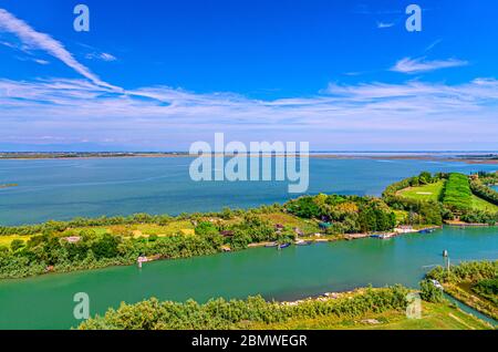 Vue aérienne des îles de Torcello, canal d'eau avec bateaux de pêche et arbres verts. Vue panoramique sur la lagune vénitienne depuis le clocher. Région de Vénétie, Italie du Nord. Fond bleu ciel nuageux. Banque D'Images