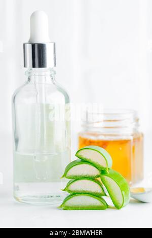 Plante naturelle biologique d'aloe vera comme ingrédients pour la préparation de lotion cosmétique maison ou huile essentielle dans des bouteilles de verre contre le dos gris clair Banque D'Images