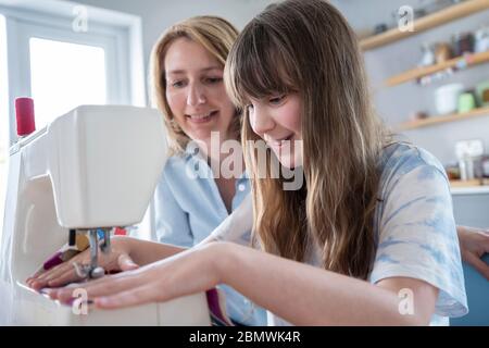 Mère fille enseignant Comment utiliser la machine à coudre à la maison Banque D'Images