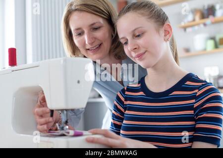 Mère enseignement adolescent fille Comment utiliser la machine à coudre à la maison Banque D'Images