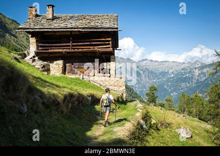 Trekking dans les Alpes dans une belle journée ensoleillée sur un sentier panoramique avec l'ancienne maison traditionnelle Walser. Vallée d'Aoste, Italie Banque D'Images