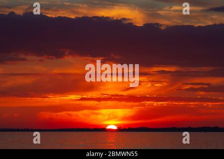 Majestueux coucher de soleil rouge-orange sur la mer. Banque D'Images