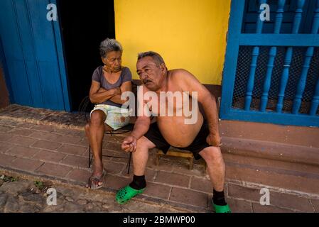 Homme et femme assis devant leur maison dans le centre de l'époque coloniale de la ville, Trinidad, Cuba Banque D'Images