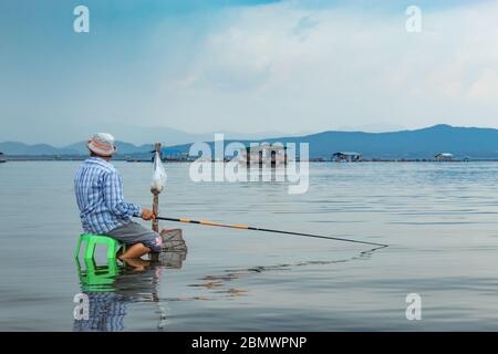 Les pêcheurs s'assoient à la pêche dans l'eau. Banque D'Images