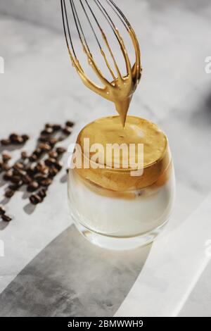 Le Dalgona tendance frogné le café dans une tasse de verre sur fond de marbre. Banque D'Images