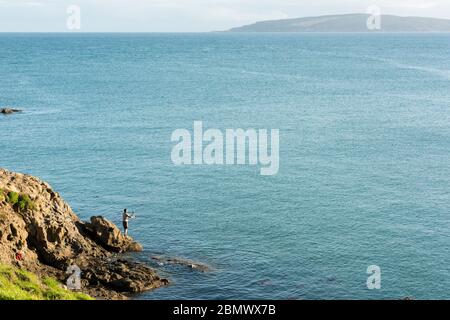 Un homme pêche en mer au large des roacks dans l'océan Pacifique Sud près de Katiki point Nouvelle-Zélande Banque D'Images