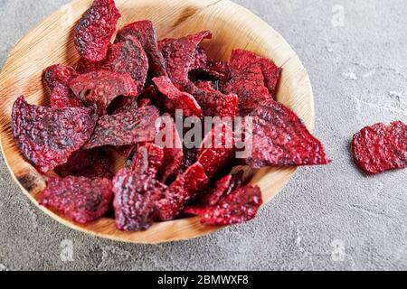 Régime alimentaire concept de saine alimentation. Copeaux de betteraves séchées ou betteraves cuites dans un bol en bois, sur fond de béton gris. Nourriture naturelle biologique. Copier l'espace. Banque D'Images