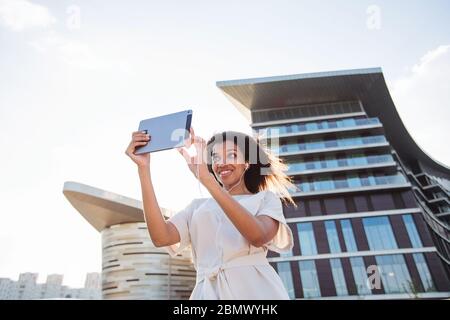 Femme passant un appel vidéo via une tablette dans une grande ville Banque D'Images