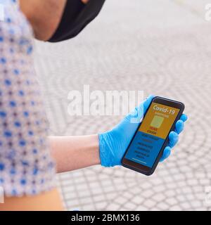 gros plan d'un jeune homme caucasien dans la rue, portant un masque noir et des gants en latex bleu, vérifiant certains des symptômes du covid-19 dans un si Banque D'Images
