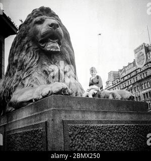 Un garçon assis sur un lion à Trafalgar Square, Londres 1955 Banque D'Images