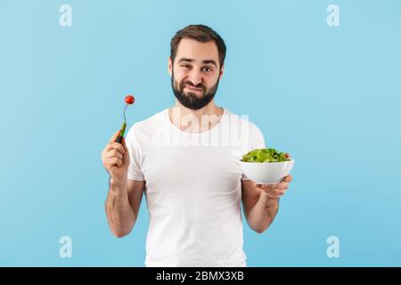 Beau déçu jeune barbu homme portant un t-shirt isolé sur fond bleu Banque D'Images