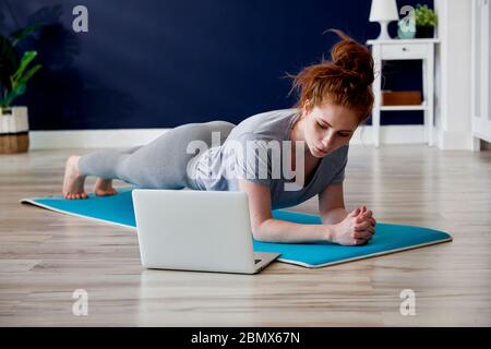 REDHEAD femme faisant quelques exercices de yoga à la maison Banque D'Images