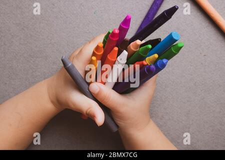 Gros plan des mains des enfants avec crayons de cire colorés. Concept d'apprentissage. Pose à plat Banque D'Images