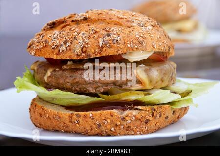 Hamburger maison fraîchement cuit avec viande, salade, oignons, concombres, tomates et ketchup Banque D'Images